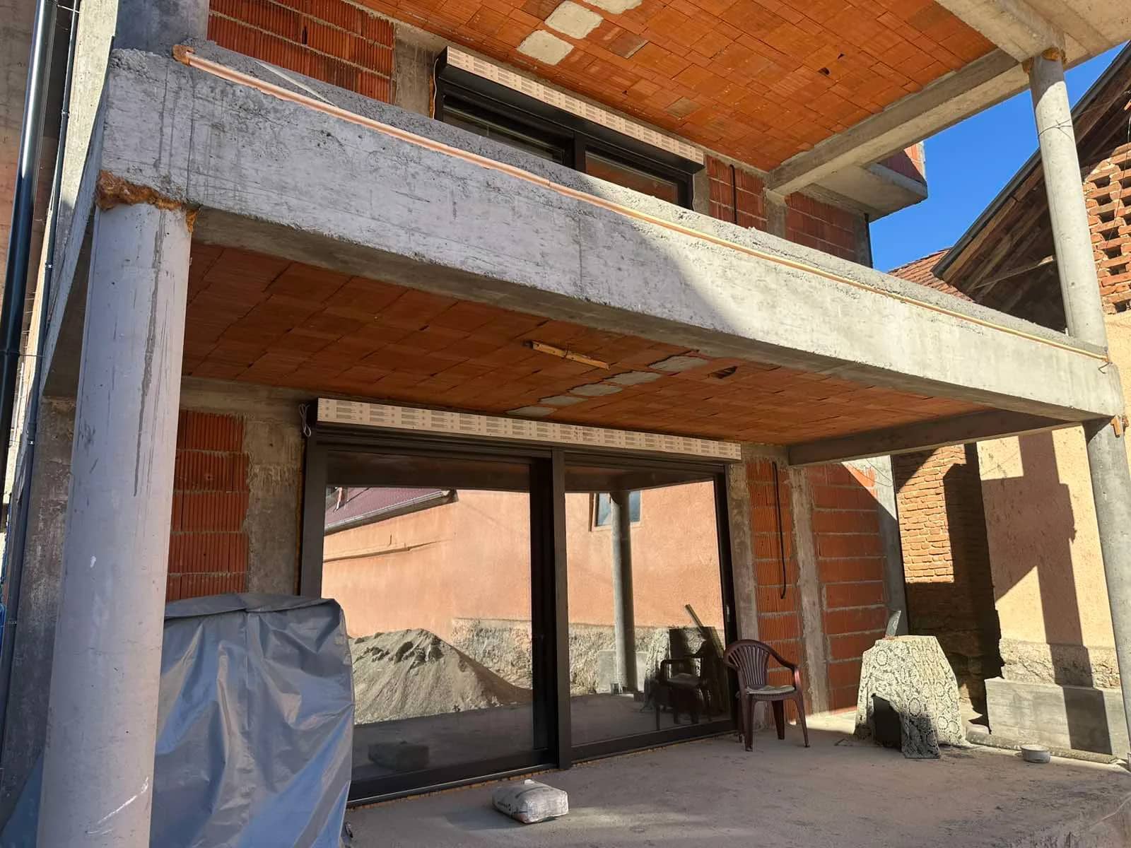 Fotografija Stalać Rezidencije u gradnji: natkrivena terasa u prizemlju sa ugrađenim kliznim staklenim vratima, ispod terase na spratu