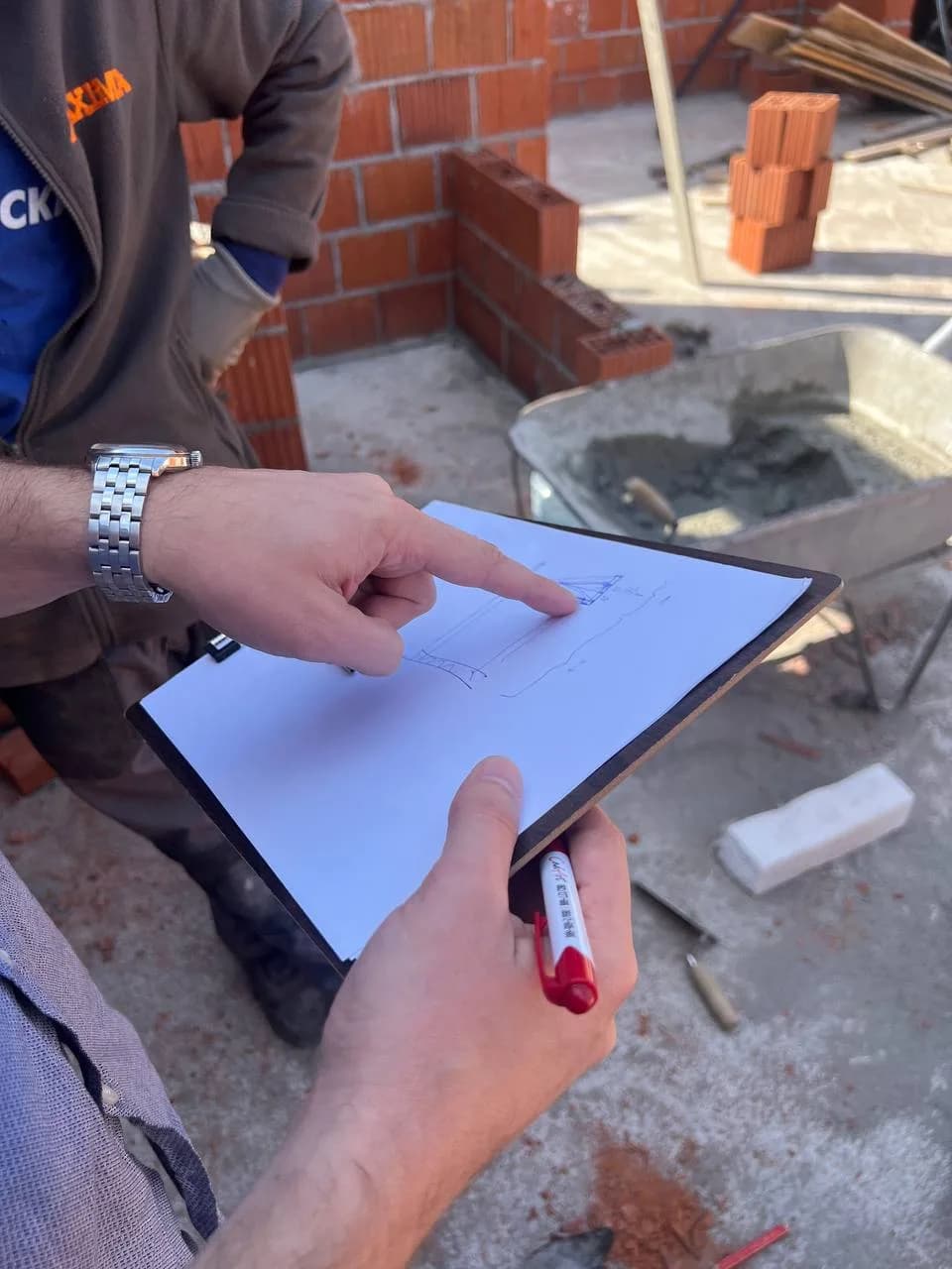 Фото: руки показывают деталь эскиза на стройплощадке