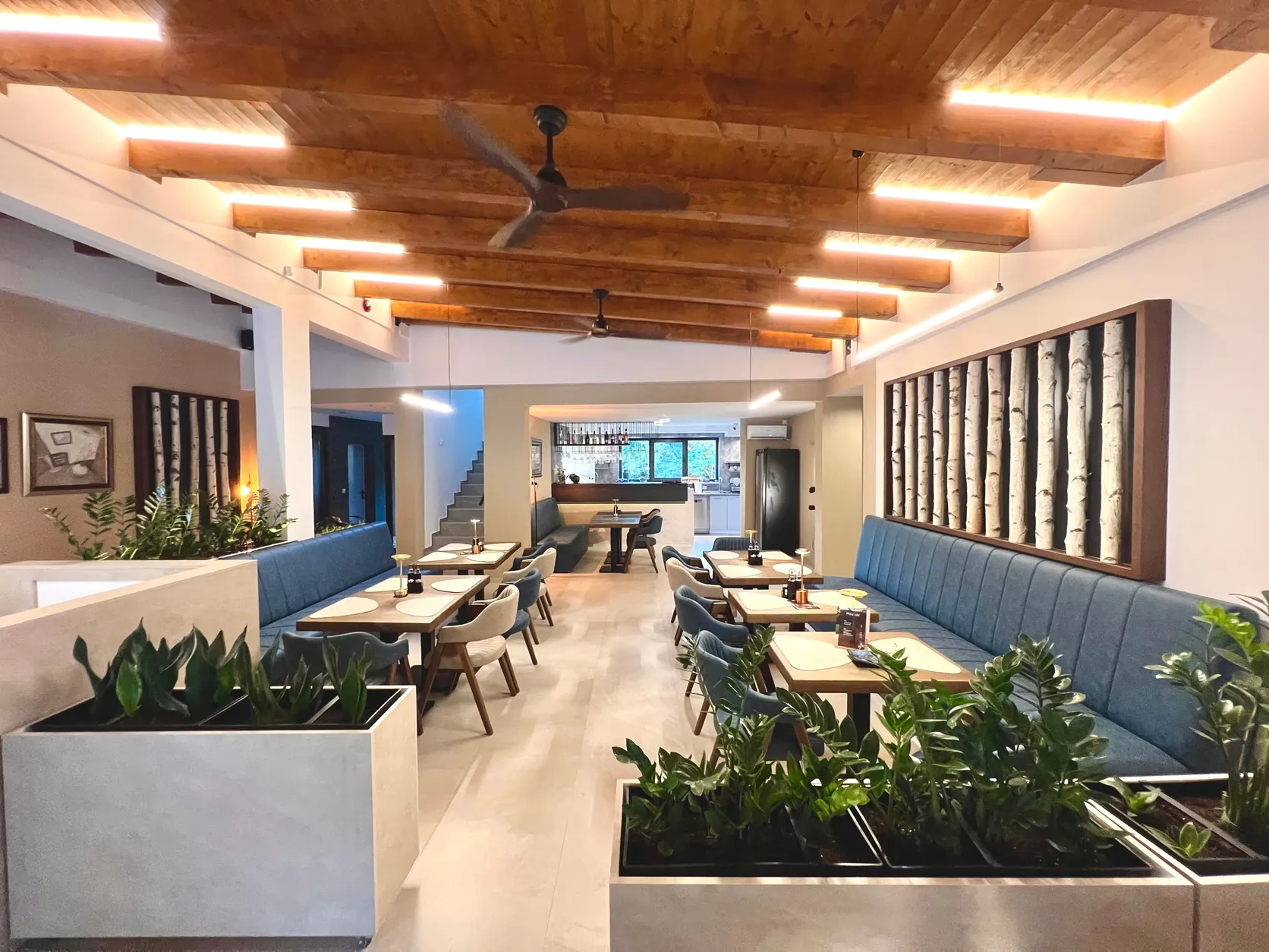 Kafe-restoran – drvena gredna tavanica sa linijskom rasvetom, tapacirane klupe, žardinjere i paneli od stabala breze