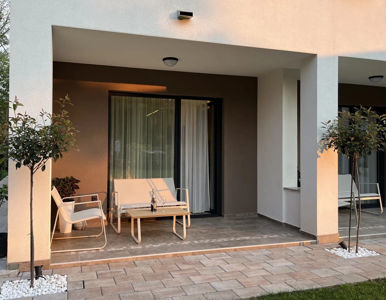 Natkrivena terasa apartmana u prizemlju sa garniturom za sedenje i izlazom na travnjak