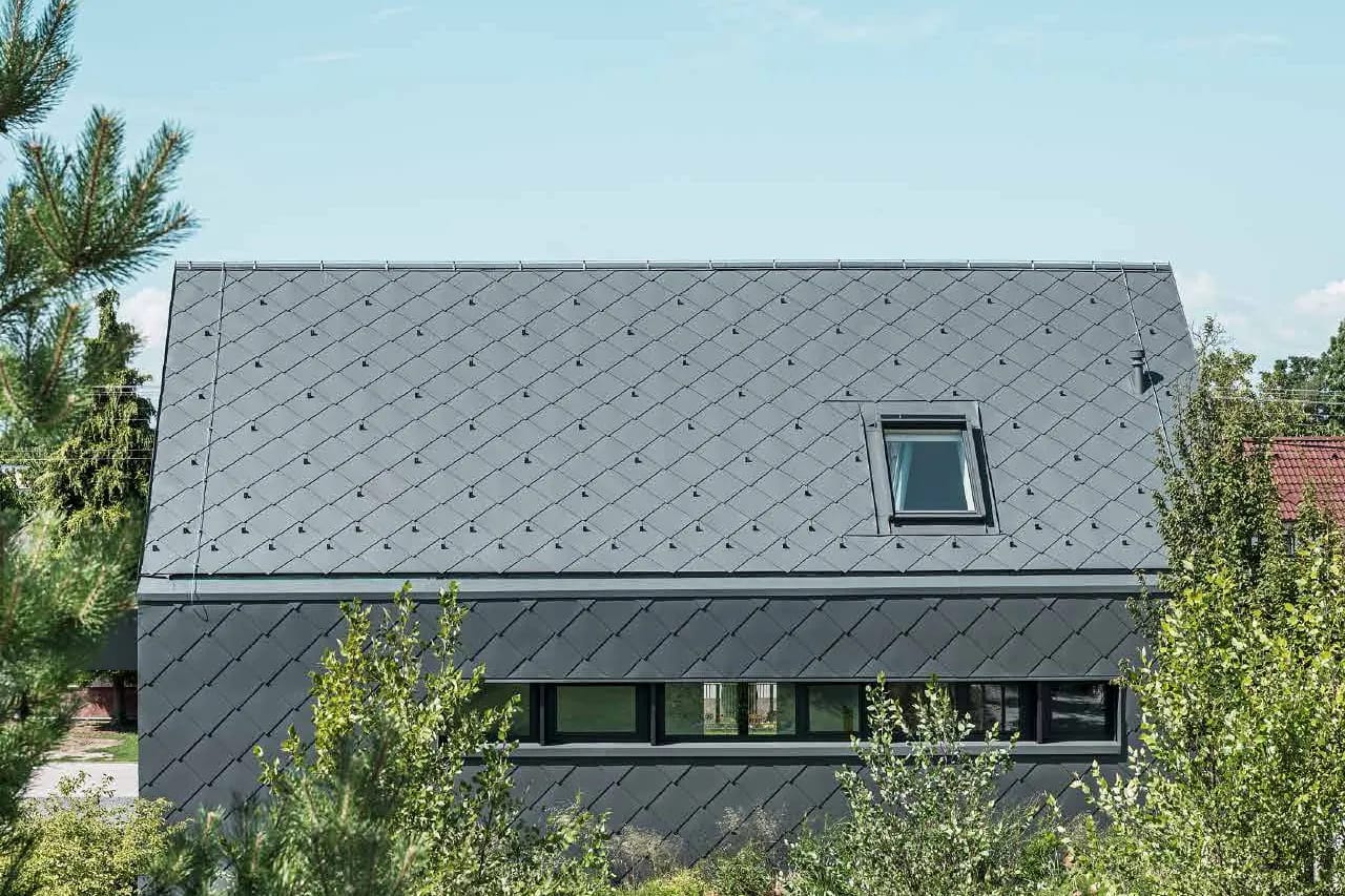 Moderna porodična kuća sa dvovodnim krovom; krov i fasada obloženi su tamnosivim PREFA aluminijumskim rombovima 44 × 44.